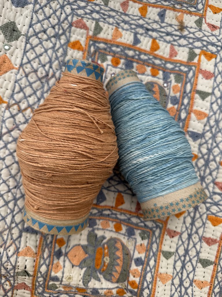 Two yarn cones on an embroidered textile